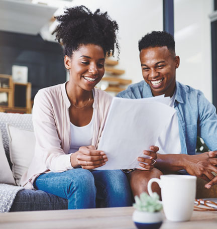 african american couple sitting on couch reading documents